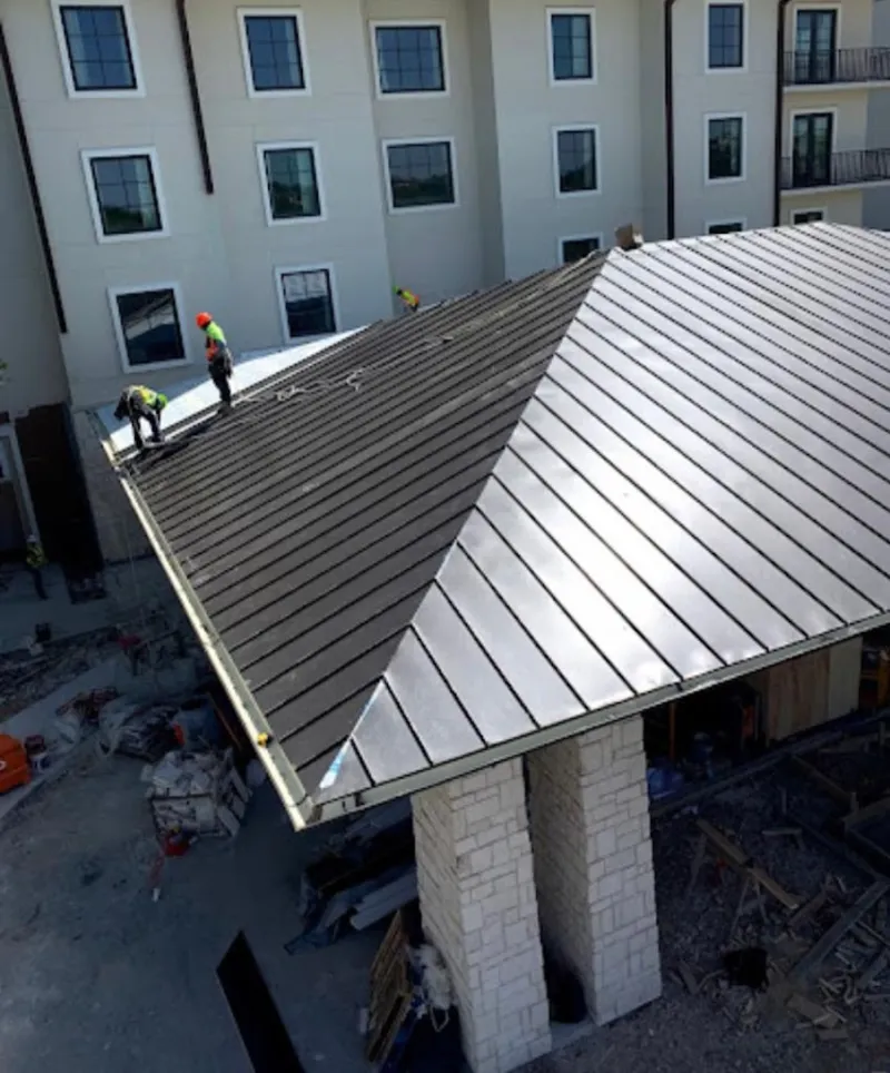 Crew installing standing seam metal roof panels on a commercial project in Red Hill